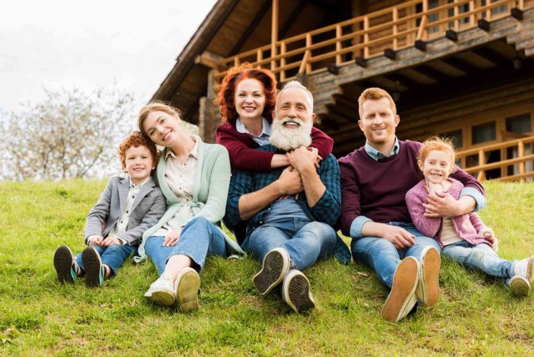 Familie sitzt am Hang vorm Haus